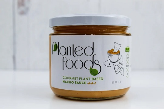 photo of vegan nacho sauce in glass container and white metal screw on lid with white paper label